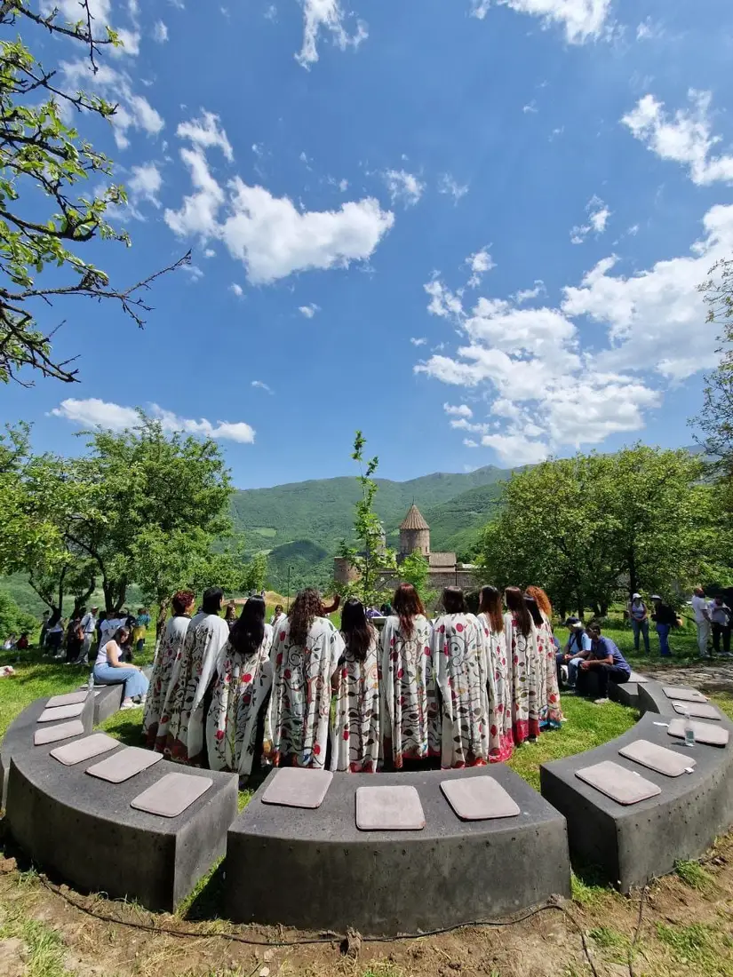 Women of the choir singing in dark robes and patterned headscarves inside a stone church