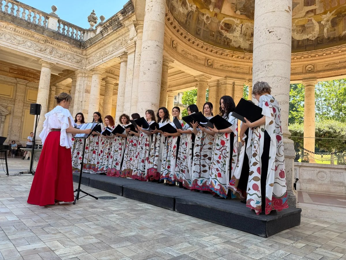 Yerevan Voices singing in traditional embroidered gowns under a historic colonnade